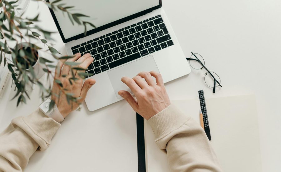 Free An overhead view of a person working on a laptop in a minimalist home office setting. Stock Photo