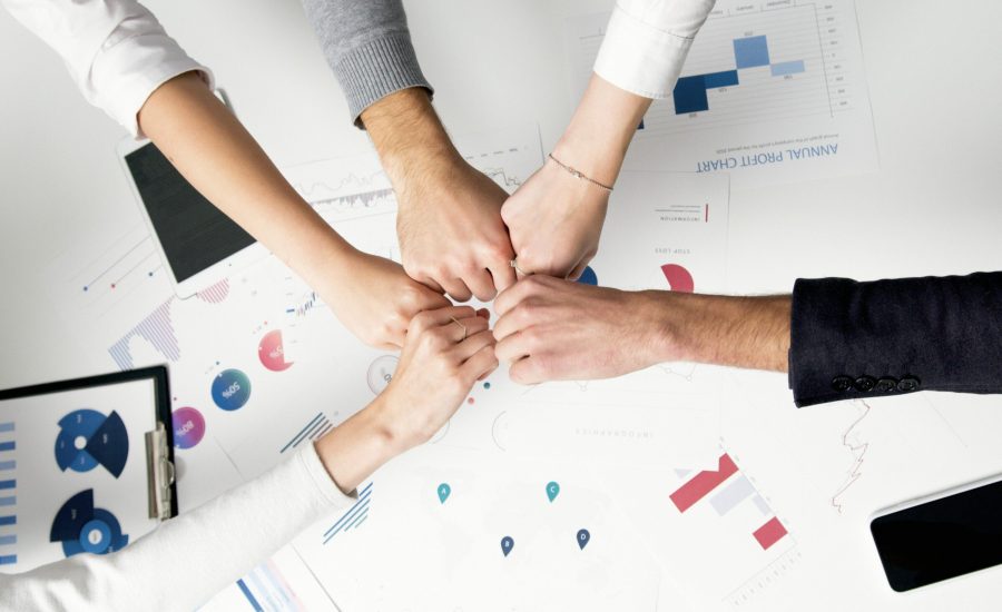 Free Colleagues celebrate success with a fist bump over financial charts depicting teamwork and unity. Stock Photo